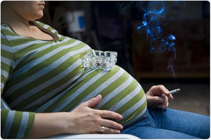 pregnant woman smoking on the bed